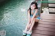 A woman in a blue bikini sitting on a wooden dock.