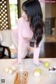 A woman in a pink shirt is bending over a table.