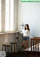 A woman standing in front of a window in a room.