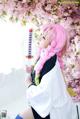 A woman with pink hair holding a sword in front of a tree.