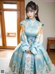 A woman in a blue and gold hanbok sitting on a bed.