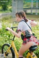 A woman in a school uniform riding a yellow bike.